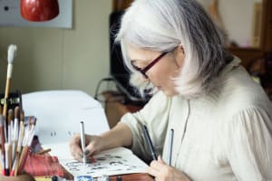 Woman uses paper and pens to create art and keep herself busy.