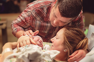 Woman and man in hospital with newborn baby.