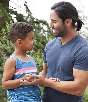 Adult and child smiling outside.