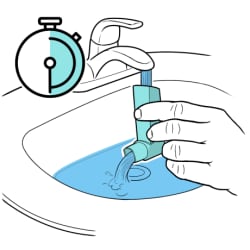 Mano sujetando un inhalador bajo el grifo, el agua entra por la parte superior y sale por la boquilla, con un reloj que muestra el paso del tiempo.