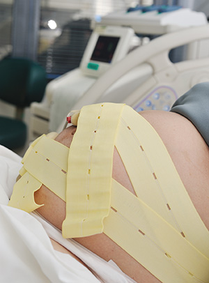 Pregnant woman lying on exam table with straps around her belly
