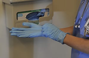 Closeup of health care provider putting on surgical gloves.