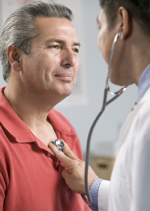 Health care provider listening to patient's chest with stethoscope.