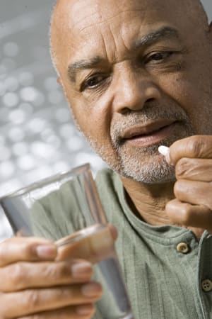 Person holding glass of water, preparing to take pill.