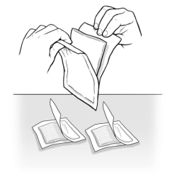 Hands opening package of gauze, and two packages of gauze laid on table, open but still inside package.