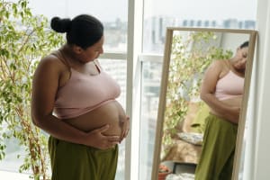 Using a long mirror to notice skin changes on a pregnant belly.