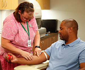 Proveedor de atención médica que extrae sangre del brazo de un hombre.