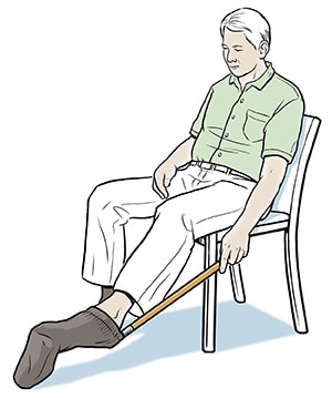 Seated person using long-handled sock aid to put on sock.