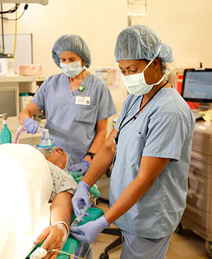 Members of care team in operating room preparing person for surgery.