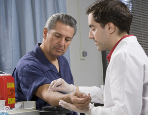 Health care provider taking blood from patient's arm.